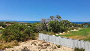 A coastal landscape with a view of the sea, a fenced area, and a path leading to a building. - Dhu View - Views for days (Guilderton)