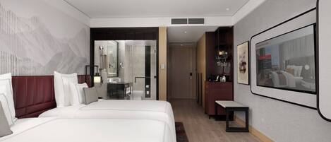 A modern hotel room with a large bed, a desk, and a bathroom visible through an open door.