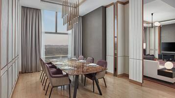 Un comedor moderno con una mesa grande dispuesta para seis personas, rodeada de sillas, en una habitación con ventanas amplias y vista a la ciudad.