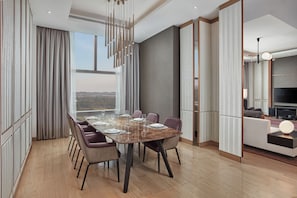 Un comedor moderno con una mesa grande dispuesta para seis personas, rodeada de sillas, en una habitación con ventanas amplias y vista a la ciudad.
