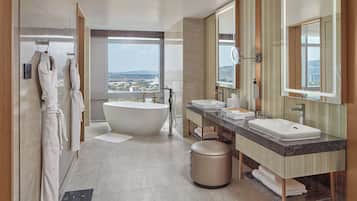 Un baño moderno con una bañera grande, dos lavamanos y un espejo amplio.
