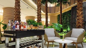 A bar area with a variety of liquor bottles and glasses, two wicker chairs, and a round table. - Swissotel Clark Philippines (Mabalacat City)