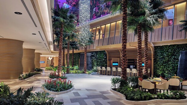 A spacious lobby with a central atrium, palm trees, and a seating area with tables and chairs. - Swissotel Clark Philippines (Mabalacat City)