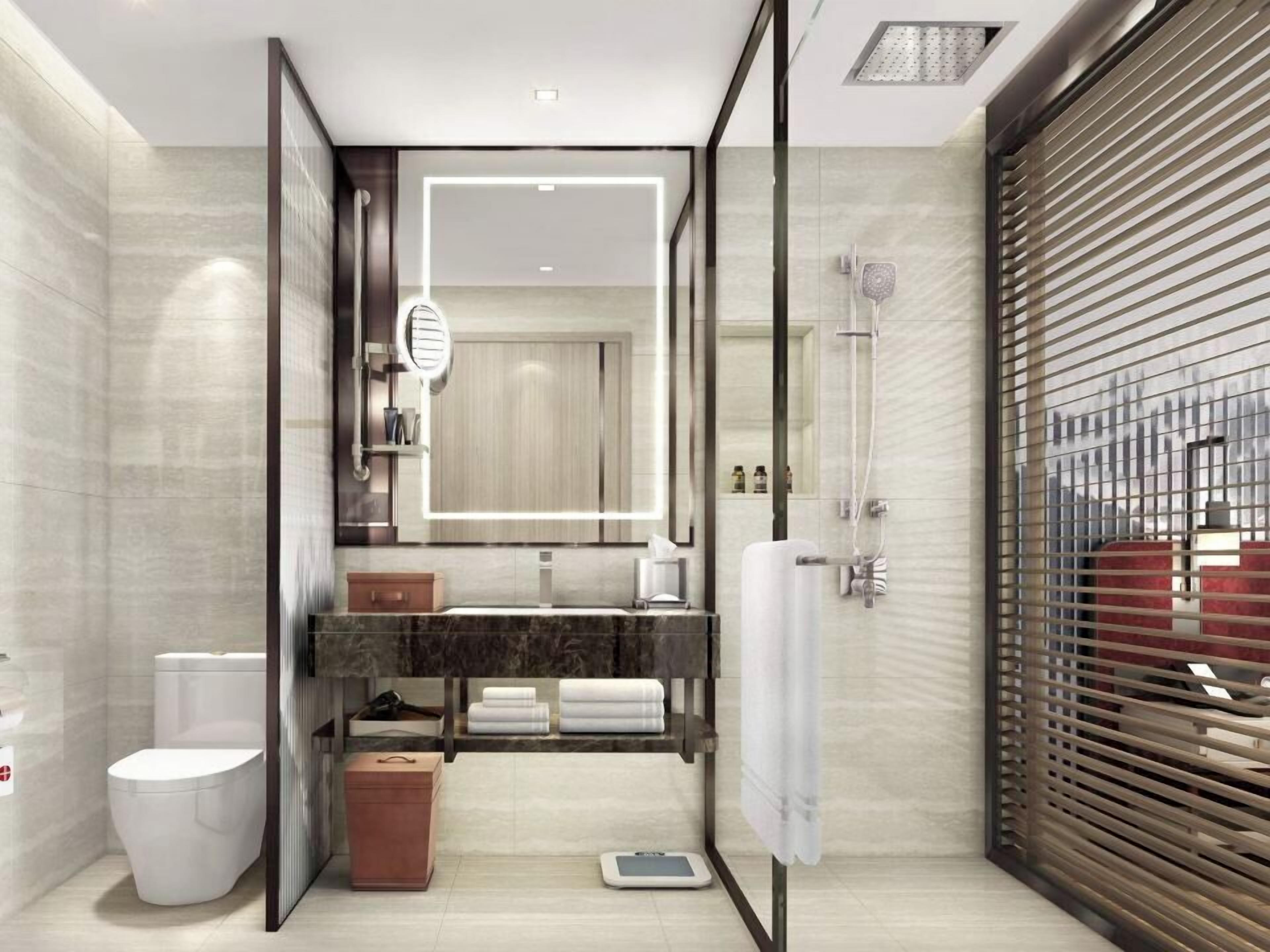 A modern bathroom with a large mirror, a shower, a toilet, and a vanity with towels.