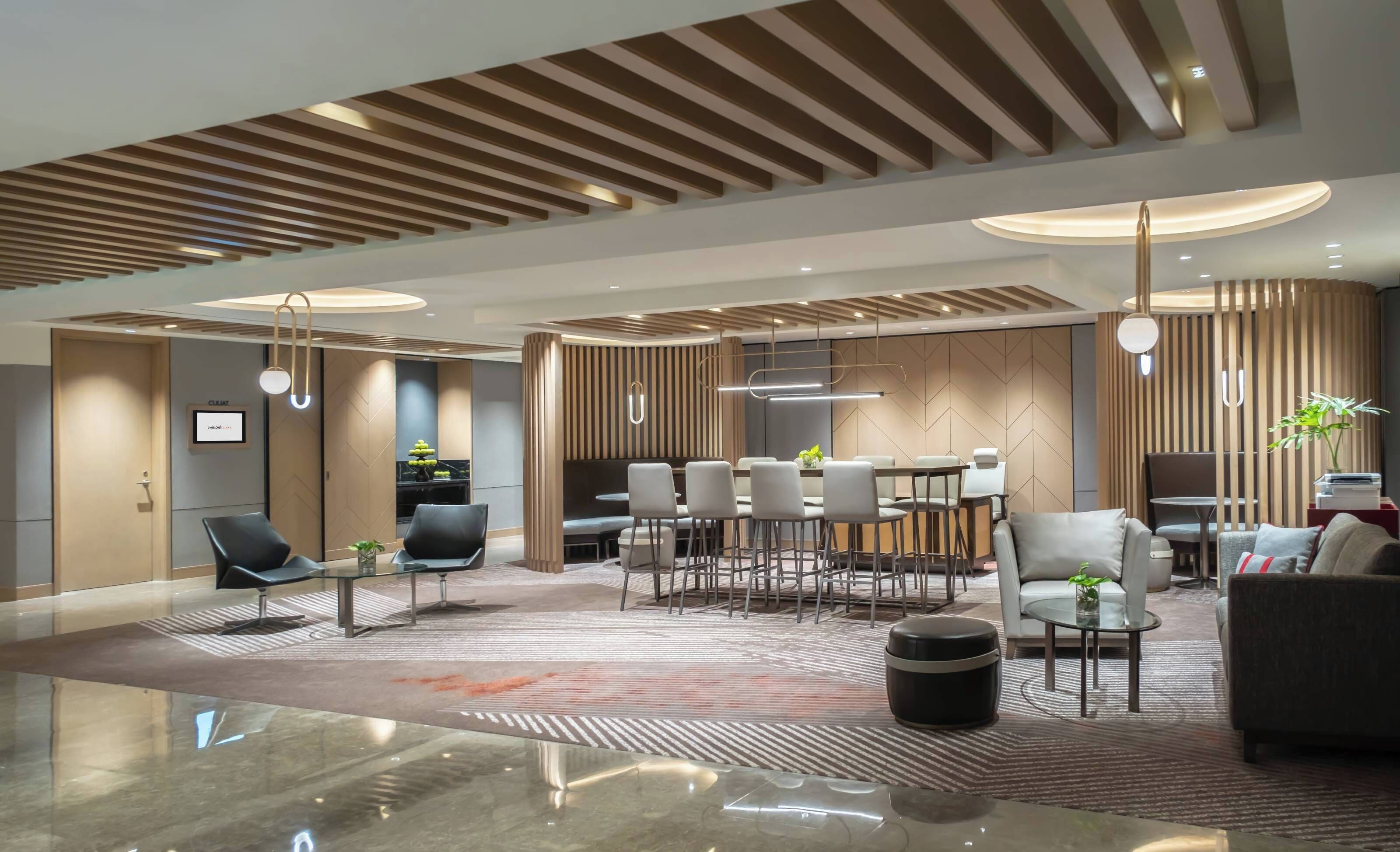 Un moderno vestíbulo de hotel con un área de estar central, un mostrador de recepción y un comedor.