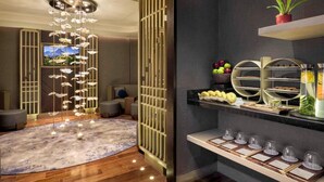 A modern interior with a decorative light fixture, a wooden partition, and a buffet area with various food items and a potted plant. - Swissotel Clark Philippines (Mabalacat City)
