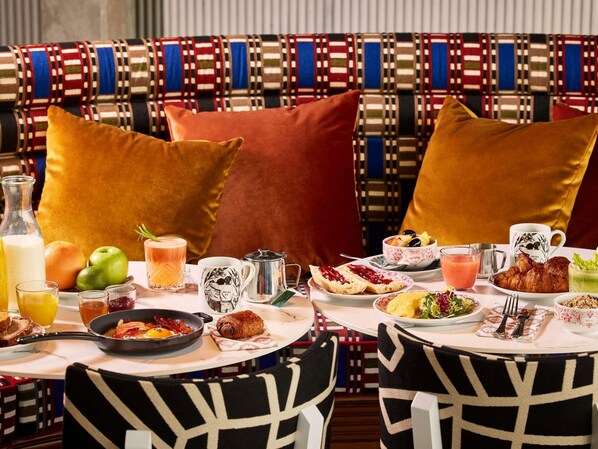 A breakfast setting with a variety of food items, a coffee pot, and a bottle of milk on a table. - Mama Shelter Paris La Défense  (Puteaux)