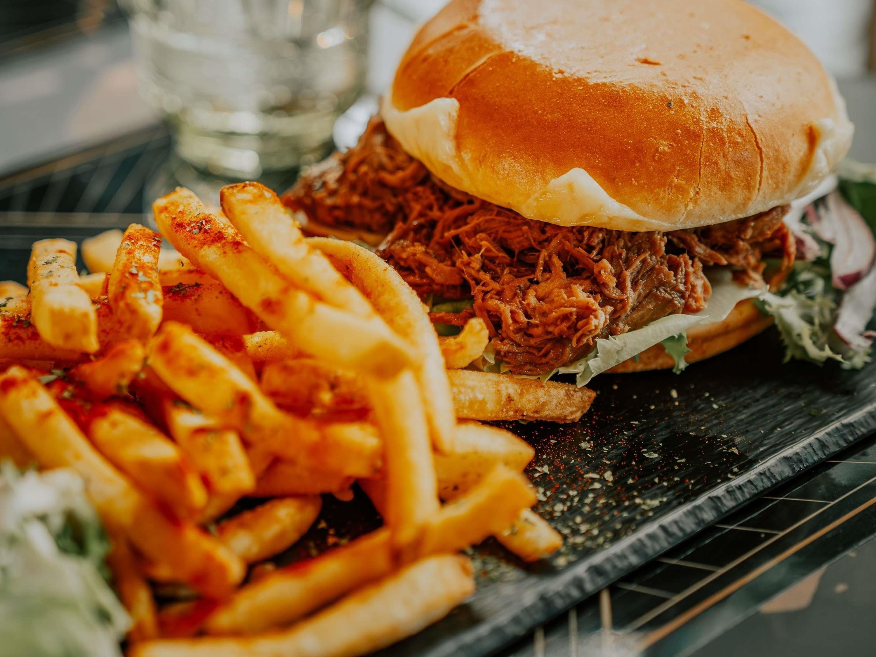 Un panino con maiale sfilacciato e patatine fritte condite.