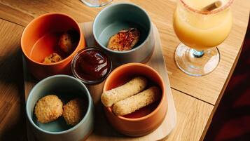 A tray with food items and a drink on a wooden table.