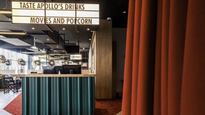 Zona de bar con un letrero que dice 'TASTE APOLLO'S DRINKS MOVIES AND POPCORN'.