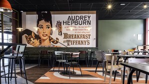 A modern restaurant interior with a large wall mural, multiple tables and chairs, and a patterned floor. - Ibis Styles Lens Centre Gare (Lens)