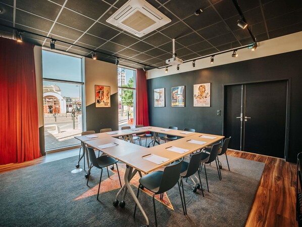 A conference room with a long table, chairs, a projector, and a door. - Ibis Styles Lens Centre Gare (Lens)