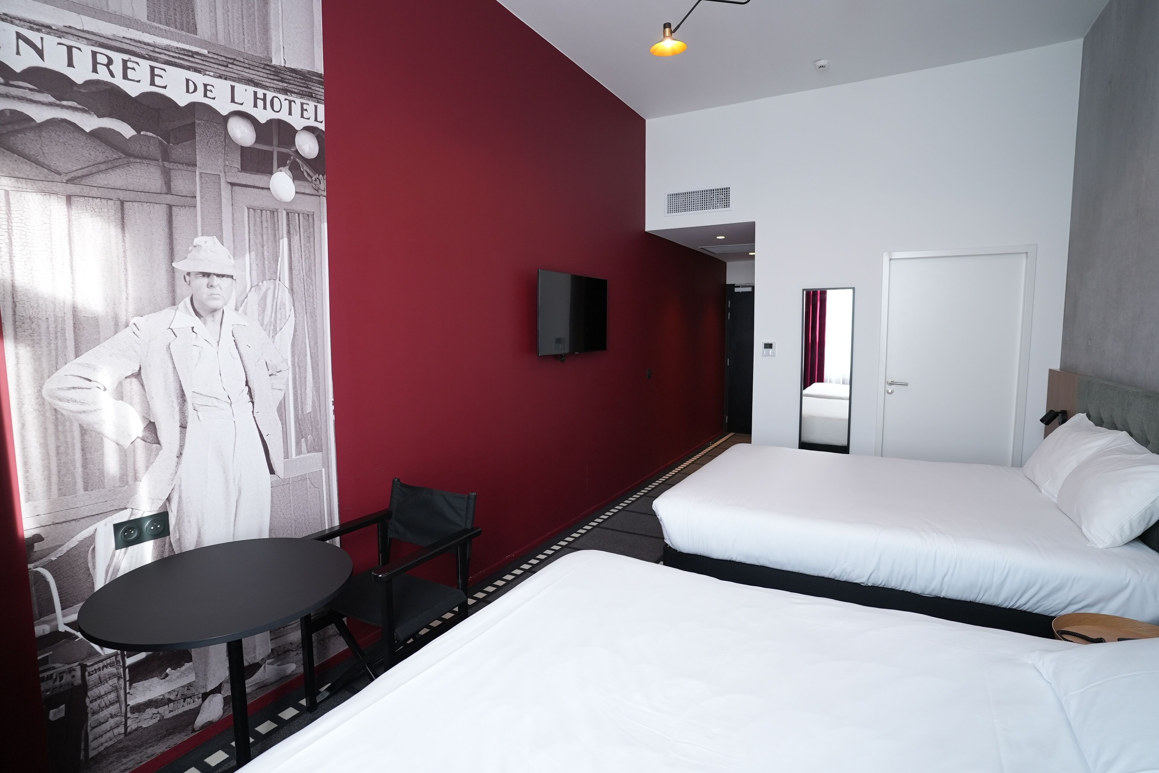 A hotel room with two beds, a TV, a chair, and a table.
