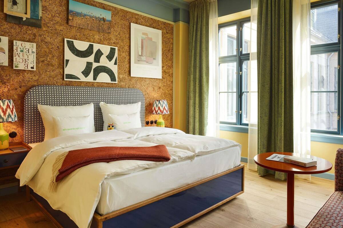 A neatly made bed with white linens, a patterned headboard, and a bedside table with a lamp.