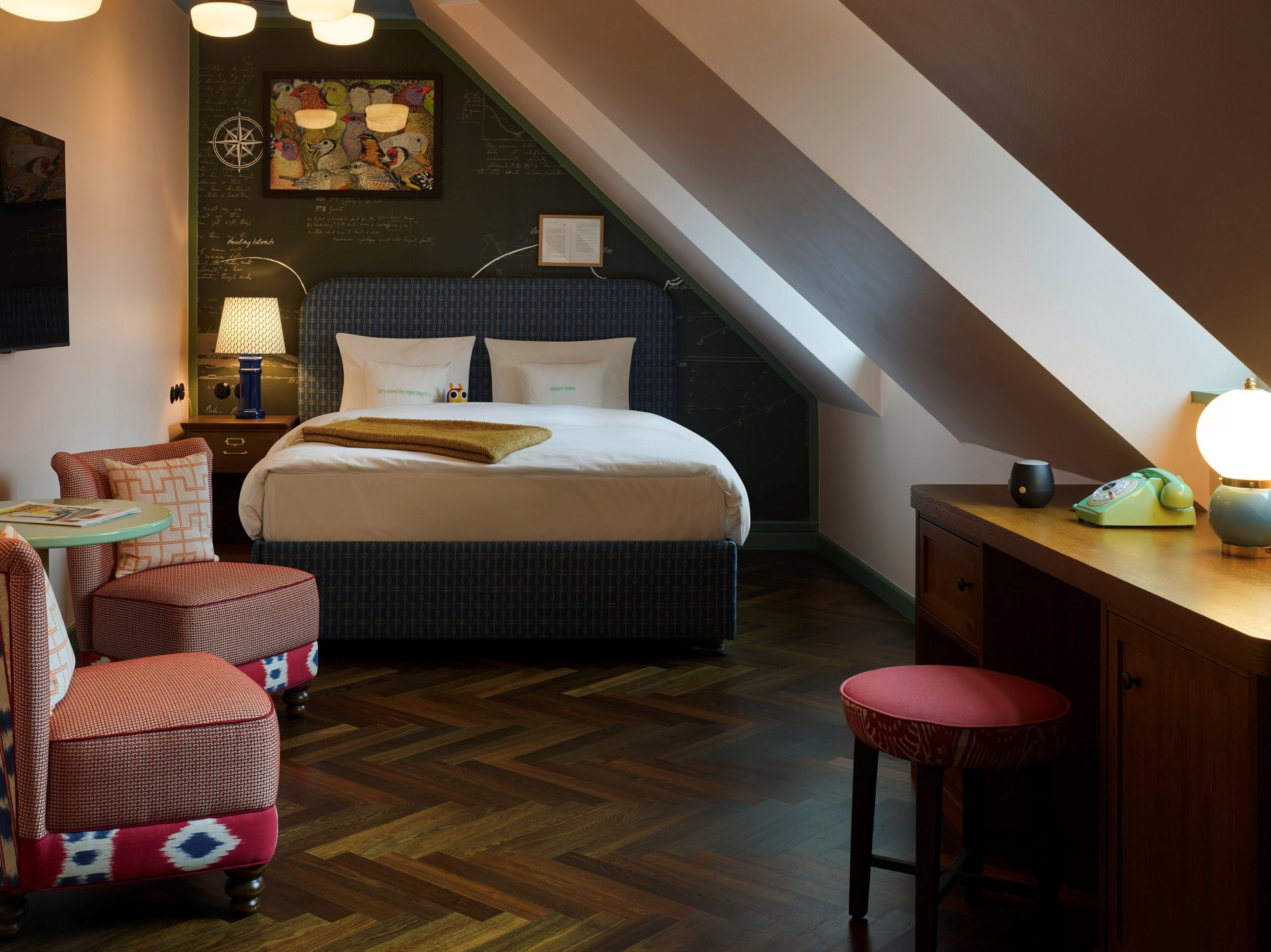 A bedroom with a bed, a desk, a chair, and a small table.
