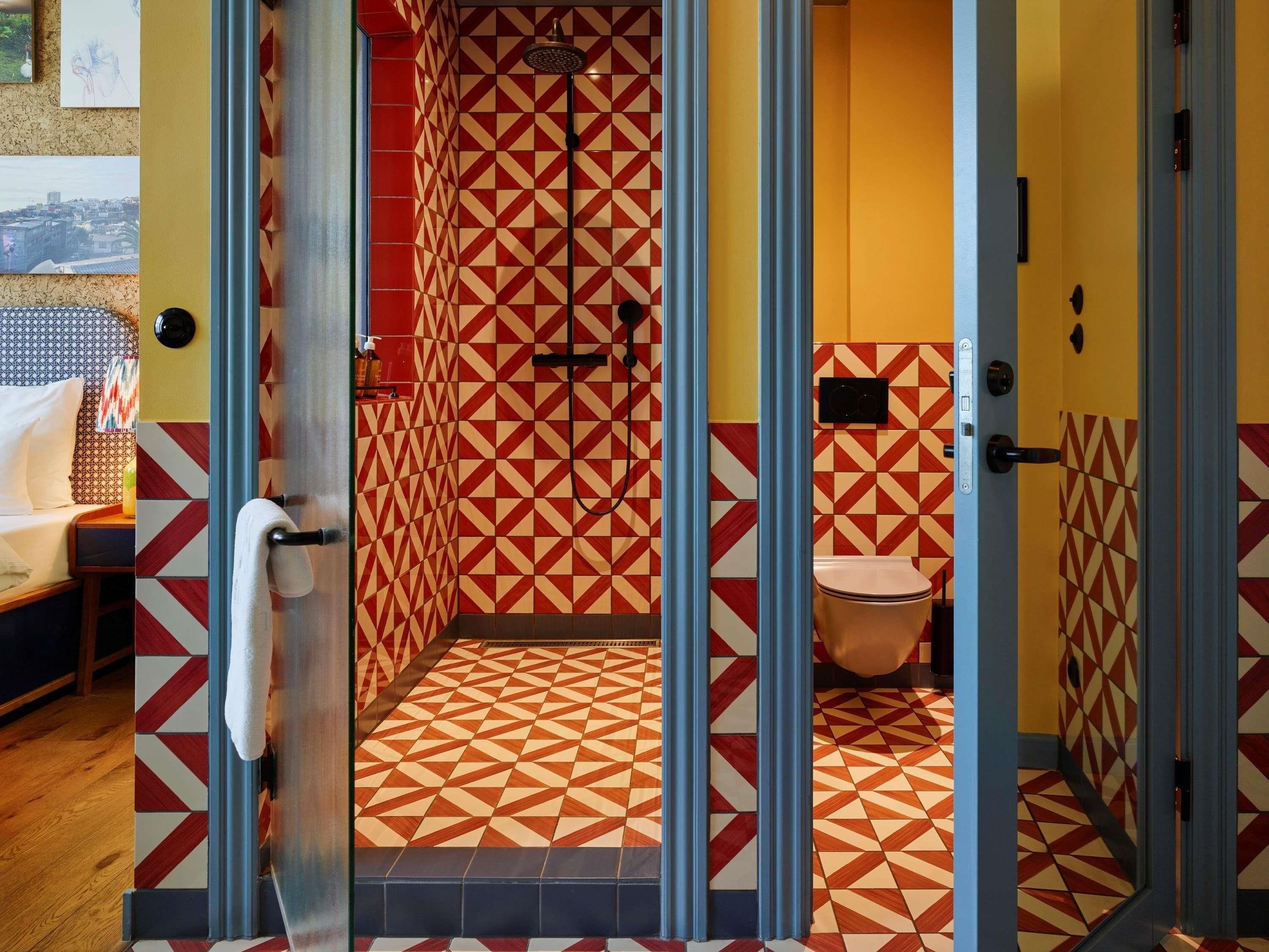 A bathroom with geometric patterned tiles, a shower, and a toilet.