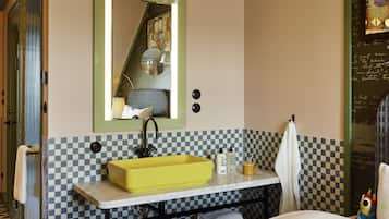 Un baño con un lavamanos amarillo, un espejo y baldosas a cuadros.