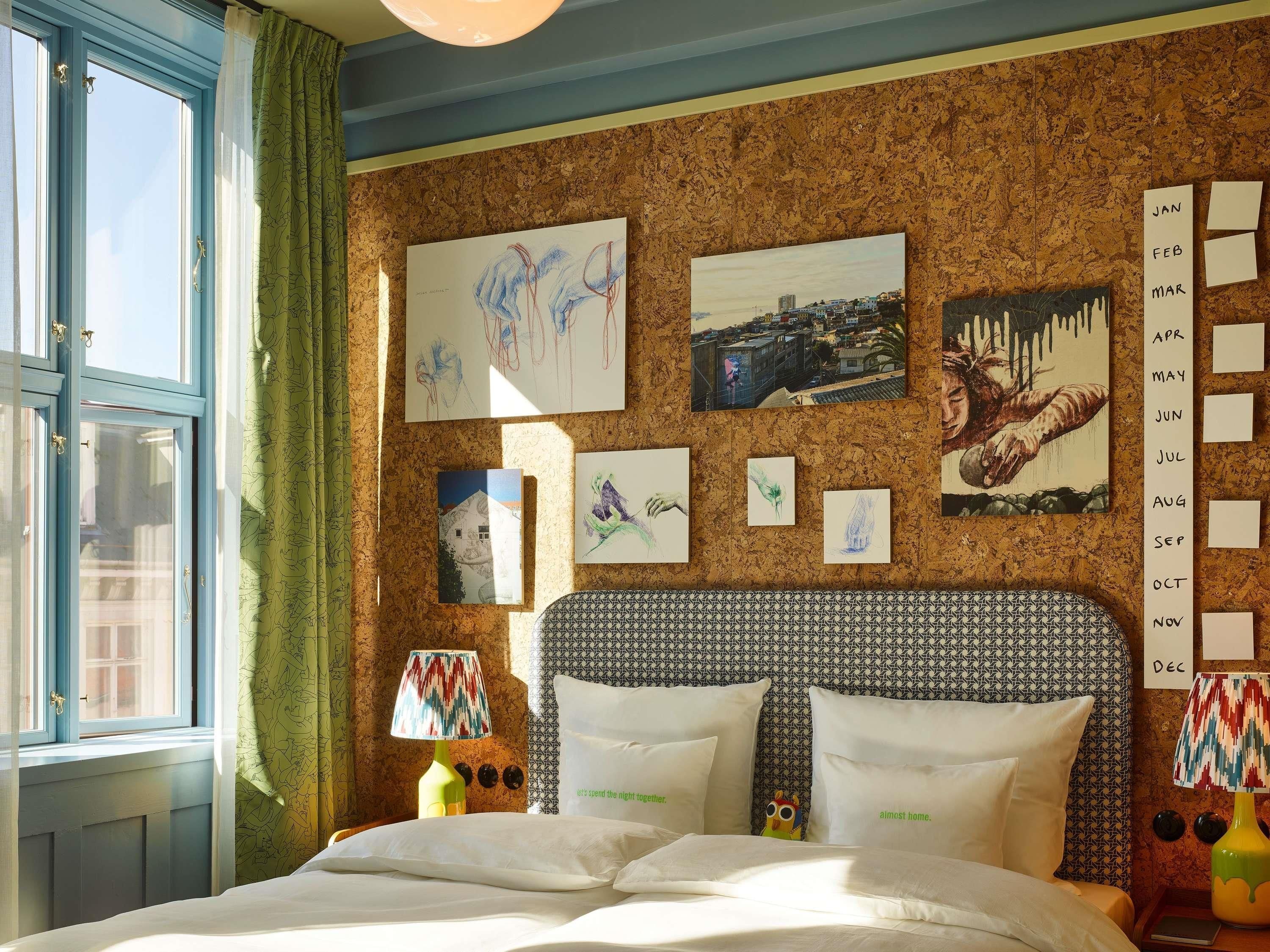 A hotel room with a bed, a wall calendar, and artwork.