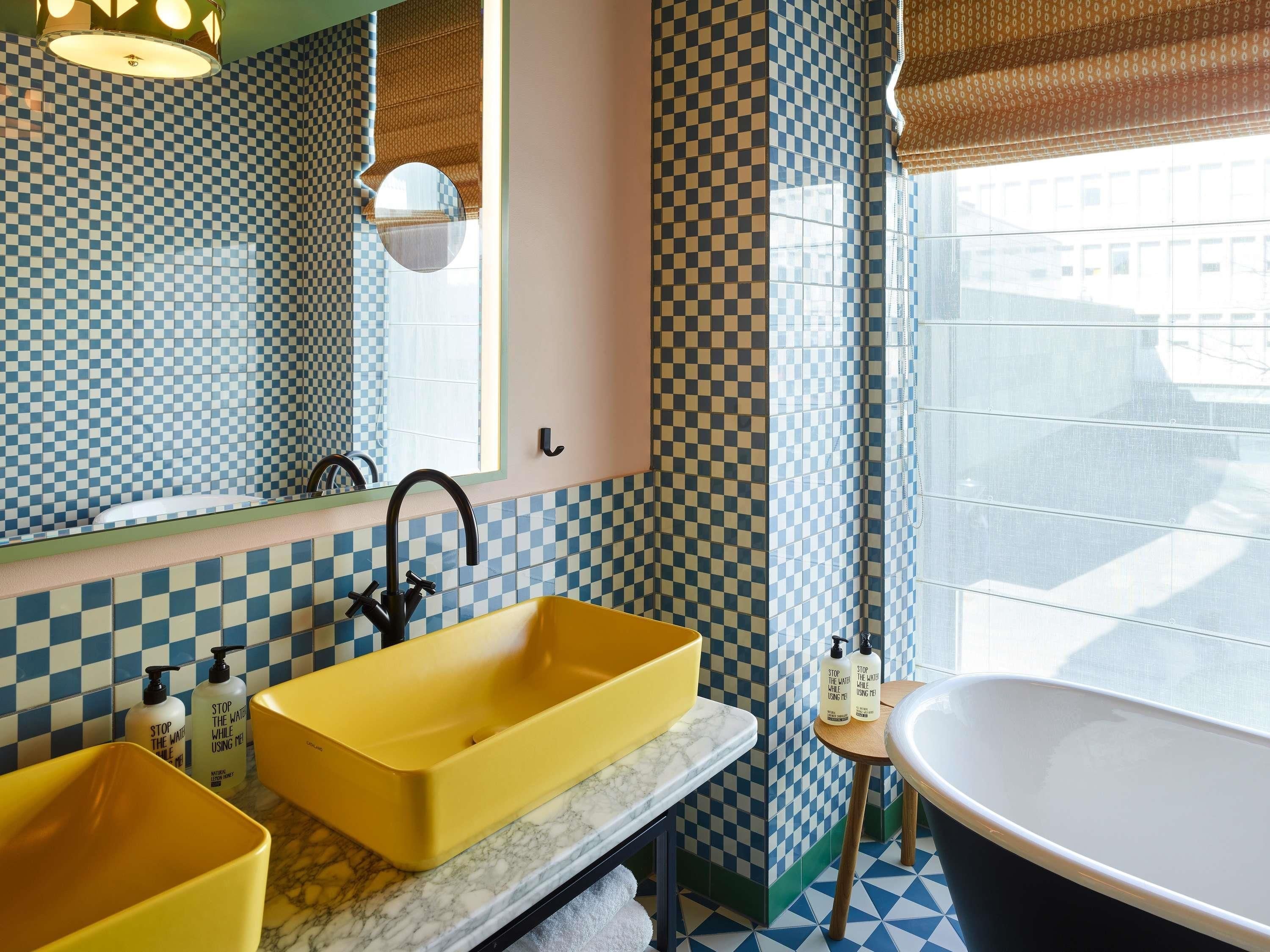 Une salle de bain avec un lavabo jaune, une baignoire et des carreaux bleus et blancs à motifs.