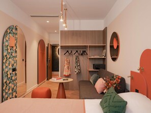 A modern bedroom with a bed, a seating area, a wardrobe, and a mirror. - Ibis Styles Sevilla Santa Justa (Seville)