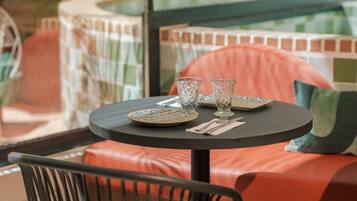 A round table with a black top, surrounded by a red cushioned bench and a black metal chair.