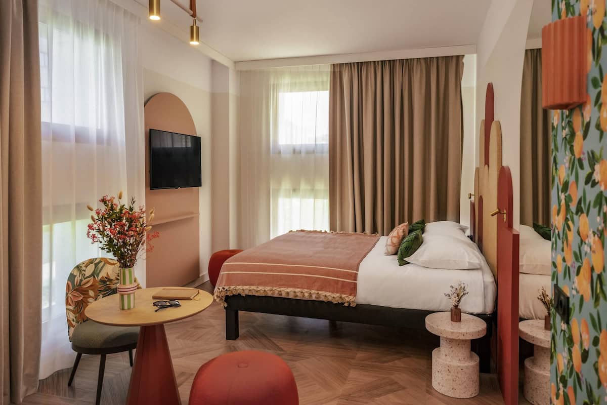 Una habitación de hotel moderna con cama, televisión, escritorio y silla.