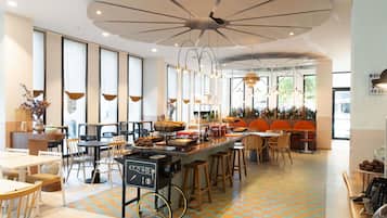 Una cafetería moderna con barra central, zona de estar y amplios ventanales.