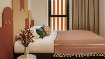 A bedroom with a bed, a round table with a vase, and a window with curtains.