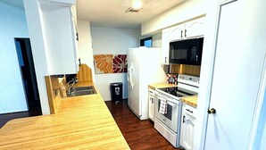 A compact kitchen with a wooden countertop, white cabinets, a microwave, and a stove. - Super Cozy 4 Bedroom by Premier Host - Sleeps 10 |  (Katy)