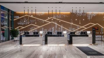 A modern reception area with a marble floor, multiple computer stations, and a cityscape light display on the wall.