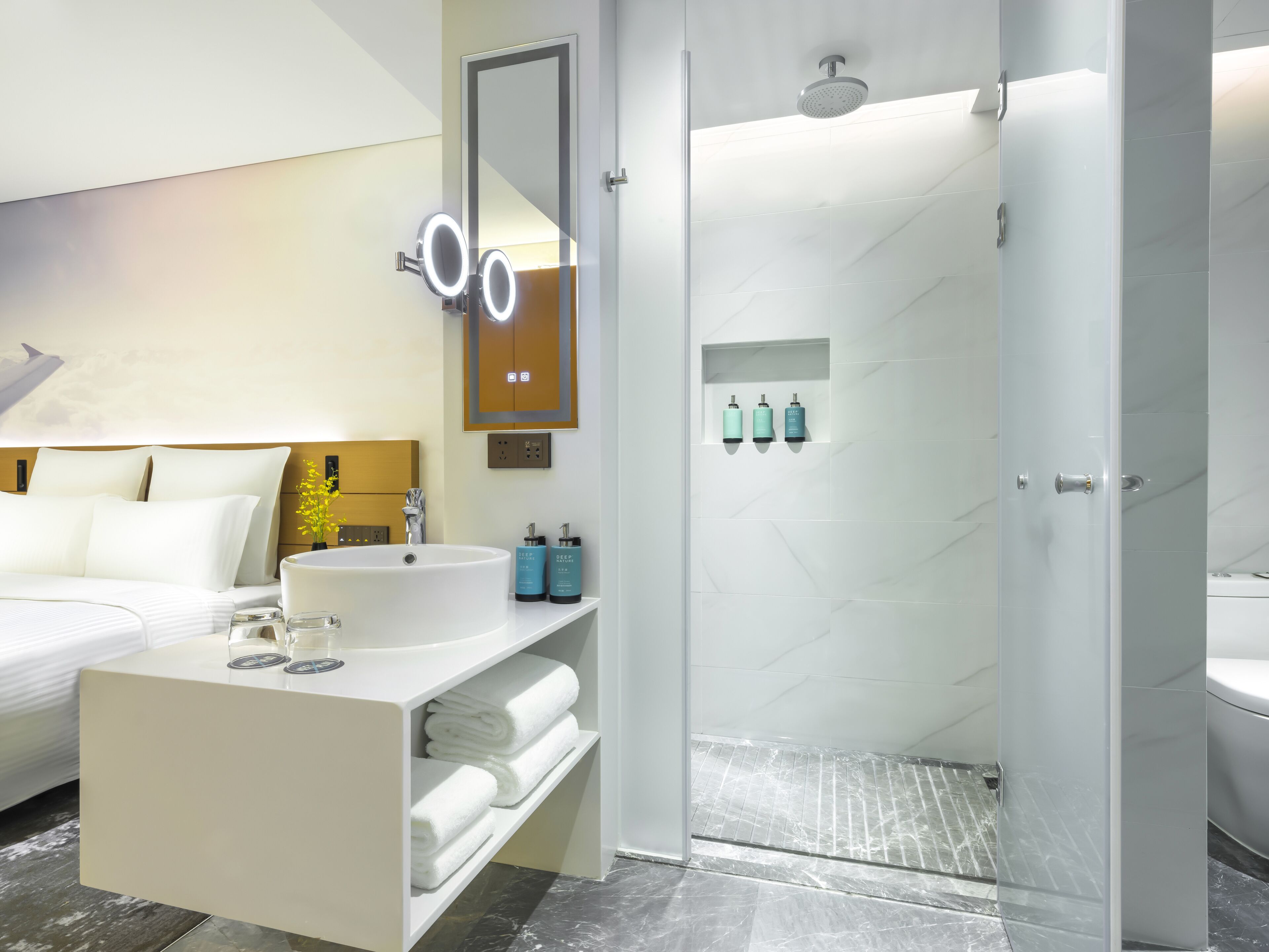 A modern bathroom with a large mirror, a sink, and a shower area.