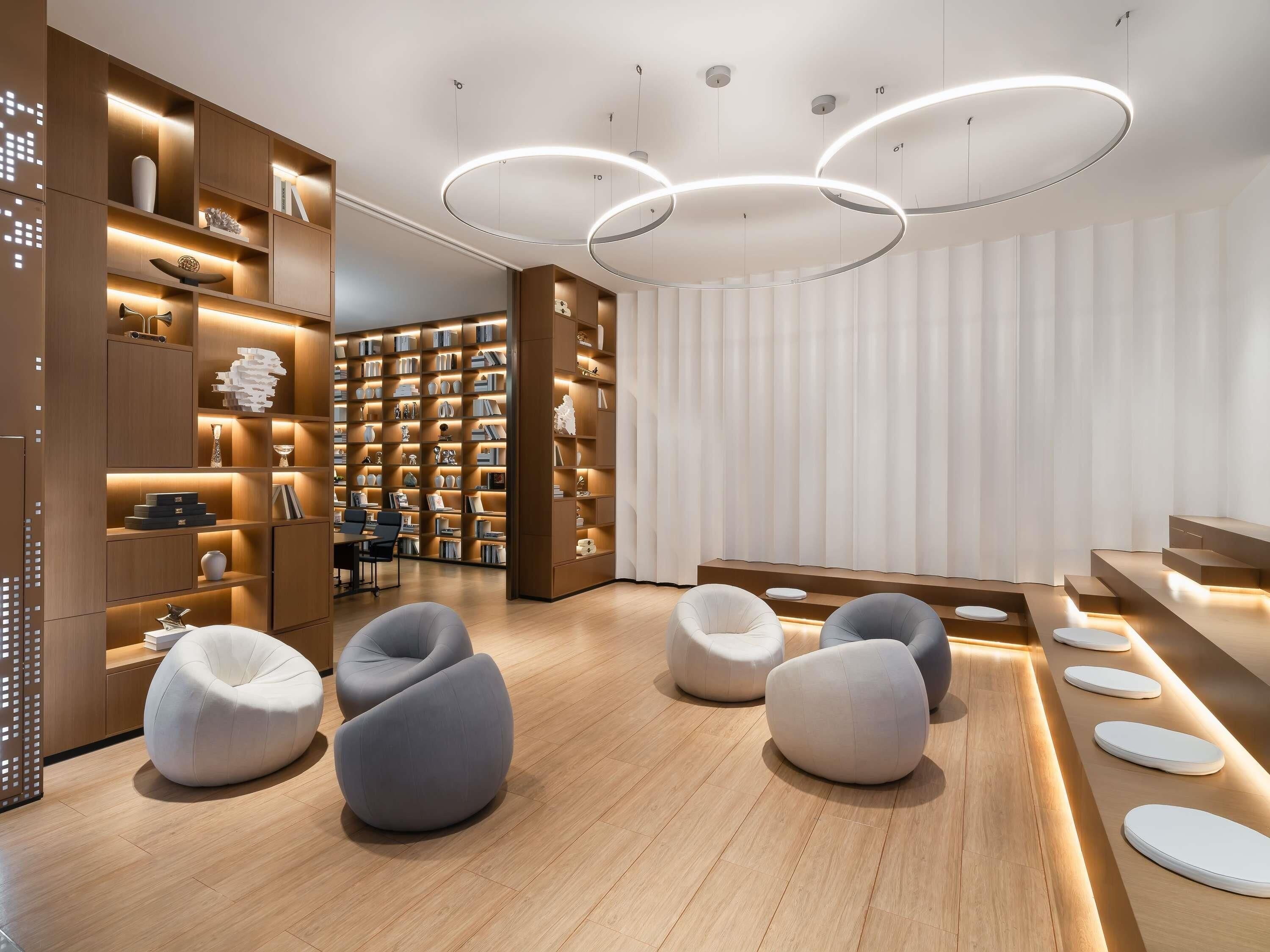 A modern library interior with bookshelves, seating, and unique lighting.