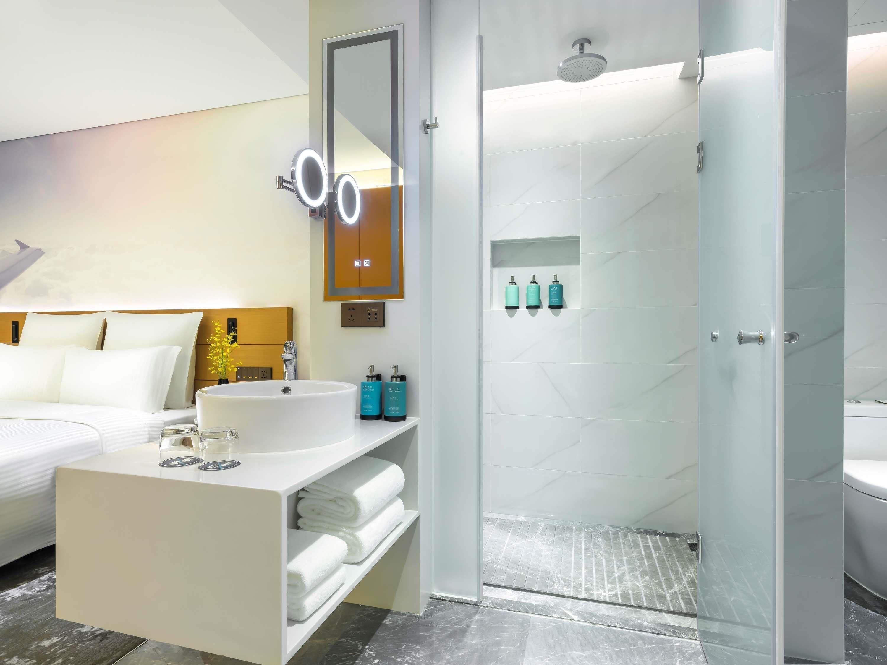 Un baño moderno con un espejo grande, un lavabo y una zona de ducha.