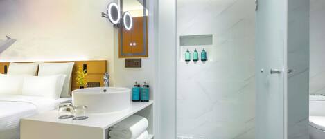 Un baño moderno con un espejo grande, un lavabo y una zona de ducha.