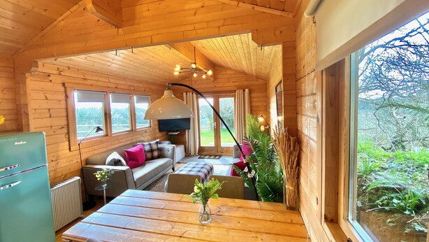Un interior acogedor de cabaña con una mesa de comedor de madera, un sofá y una televisión.