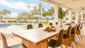 A wooden dining table with chairs, a bowl of fruit, and a bottle of water. - Sunridge by AvantStay | Glorious Estate w/ Pool, Hot Tub, Ping Pong & Pool Table (Scottsdale)