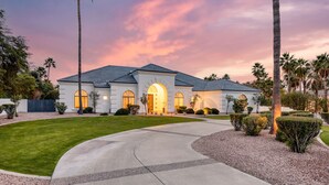 A modern two-story house with a curved driveway, surrounded by well-maintained landscaping and palm trees. - Sunridge by AvantStay | Glorious Estate w/ Pool, Hot Tub, Ping Pong & Pool Table (Scottsdale)