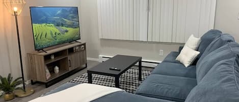 Una sala de estar moderna con un televisor de pantalla plana grande, un sofá, una mesa de centro y una lámpara de pie.