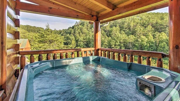 A hot tub in a wooden cabin with a view of a forested landscape. - Cozy Mountain Retreat, Open Concept, 7 Min To GSM Parkway, 5Br/5Ba, King Beds, (Sevierville)