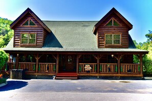 A log cabin with a front porch, two chimneys, and a sign indicating it is a historic site.