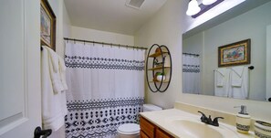 Ein Badezimmer mit Duschvorhang, Toilette, Waschbecken und Ablagefläche mit Pflanze.