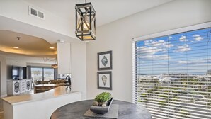 A modern kitchen with white cabinetry, a dining area with a round table, and a large window with blinds. - IR 619 3 bed/2 bath. Unit comes with Free Beach Service (Destin)