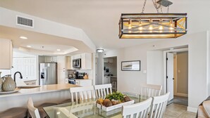 A modern kitchen with white cabinetry, a central island with seating, and a hanging industrial-style light fixture. - IR 619 3 bed/2 bath. Unit comes with Free Beach Service (Destin)