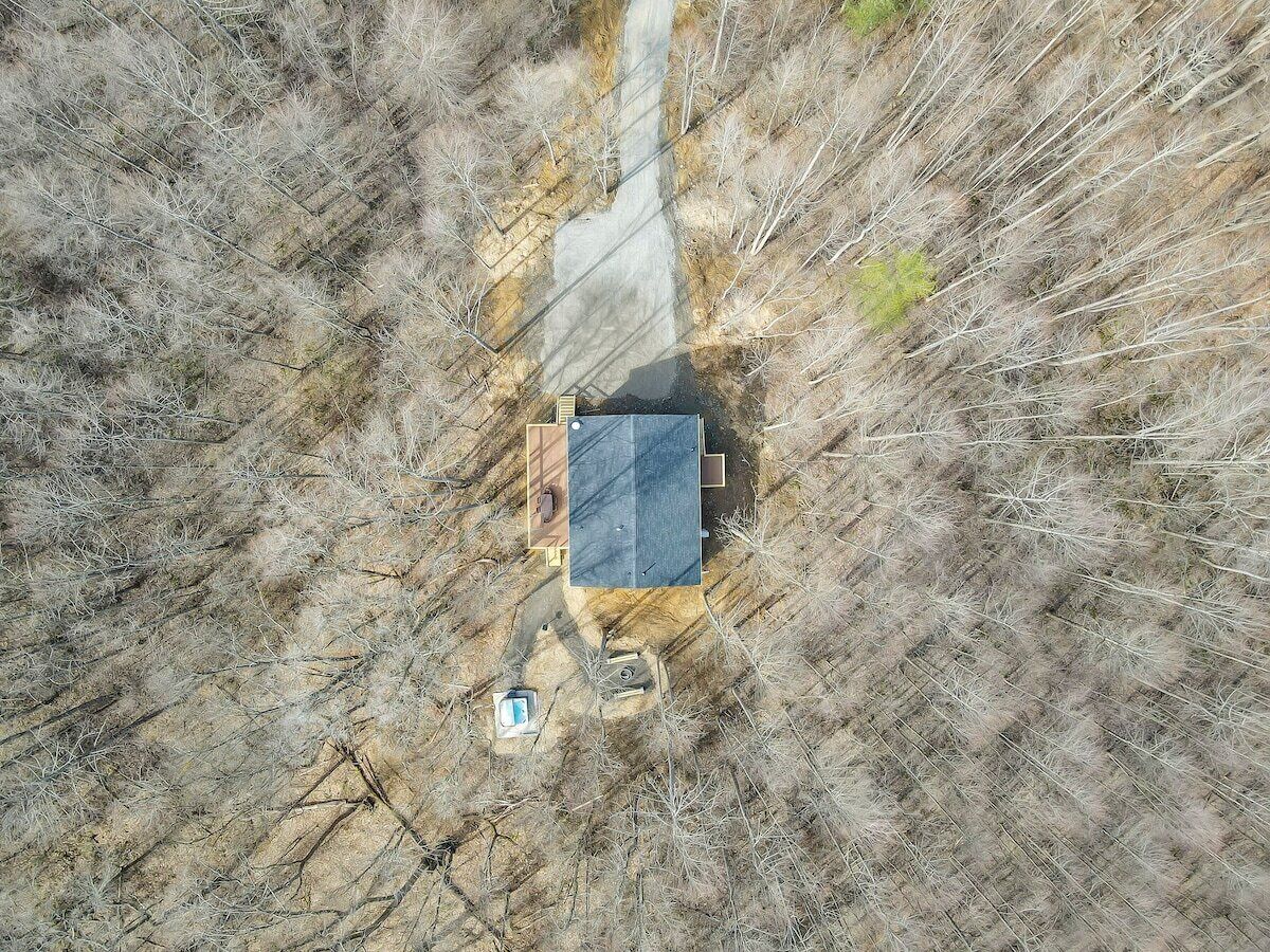 An aerial view of a house with a dark roof, surrounded by dry grassland.