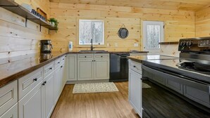 A modern kitchen with wooden walls, a built-in dishwasher, and a stainless steel stove.