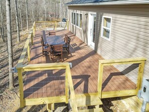 A wooden deck with a table and chairs, surrounded by a wooden fence, and a building with windows and a door. - Deerberry Ridge (Hocking Hills Area) (Rockbridge)