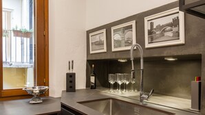 Una cocina con un lavamanos de acero inoxidable, copas de vino y una botella de vino.