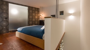 Un dormitorio con cama, armario, espejo y lámpara.