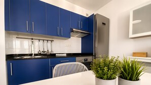 A modern kitchen with blue cabinets, a stainless steel refrigerator, and a white countertop. - Appartement Villalia  (Puerto del Carmen)