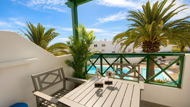 A balcony with a view of a swimming pool, a table, and chairs. - Appartement Villalia  (Puerto del Carmen)